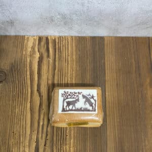 Brown wrapped soap bar on a wooden surface with a white label showing two dark animal silhouettes under a tree.