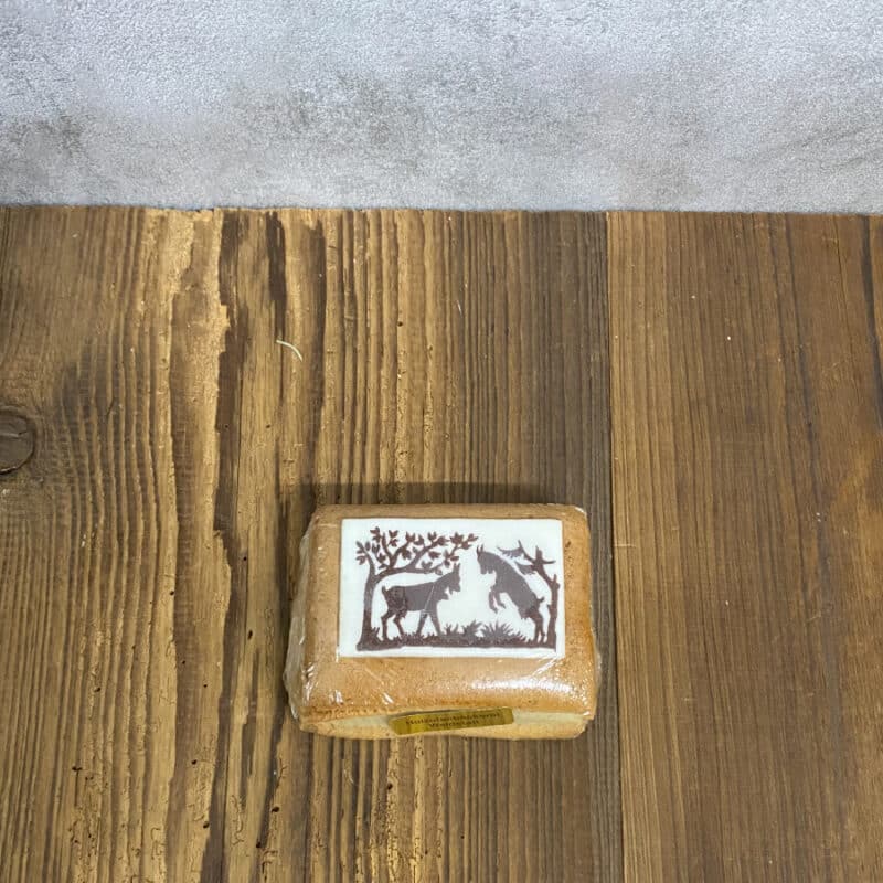 Brown wrapped soap bar on a wooden surface with a white label showing two dark animal silhouettes under a tree.