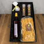 Gift box with wine, ribbon-wrapped cheese, salt and pepper grinders, and dried pasta on a wooden surface