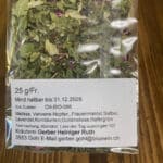Bag of loose herbal tea with a label listing ingredients and producer contact information.