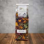 Transparent bag of colorful dried flower petals labeled 'Ballerina' on a wooden table, herbal tea blend from Kräuterei (Swiss organic herbs).
