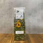 Tall clear bag of Morgenfrische herbal tea with dried greens and yellow flowers on a wooden surface; label shows Kräuterei branding and Swiss bio logos.