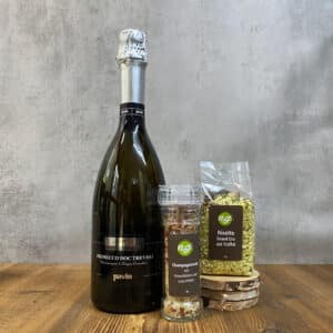 Prosecco DOC Treviso bottle with foil cap, beside a spice grinder and a bag of truffle risotto on a wooden table.