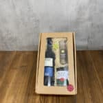 Gift box with a window showing a wine bottle, a spice jar, and a jar labeled Wein Risotto nestled in straw.